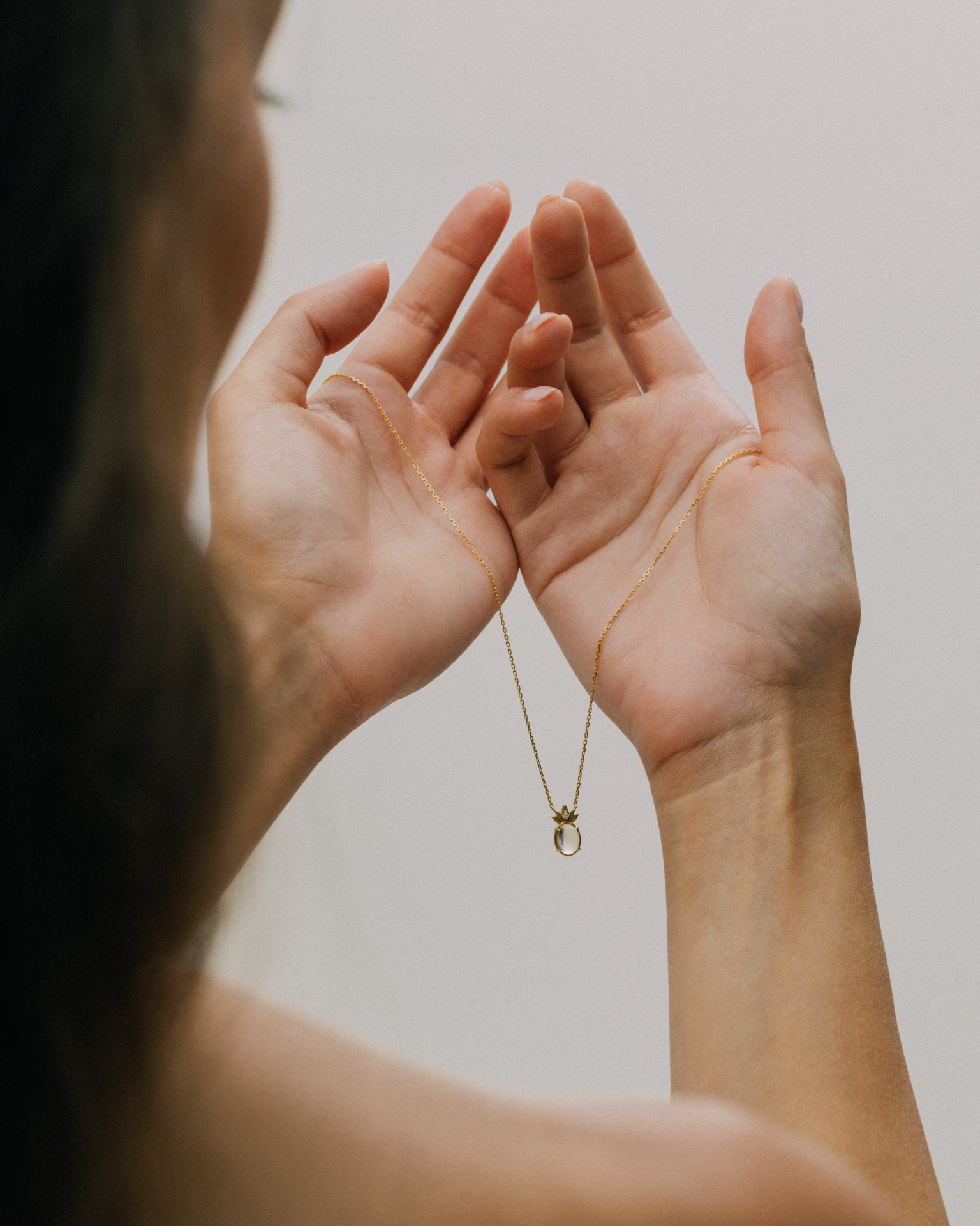 A woman holding the complete THALYRA necklace between both hands